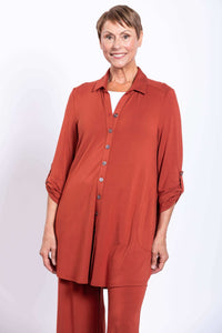 Front view of model wearing rust-colored oversized button-up blouse with adjustable sleeves