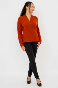 Three-quarter body shot of model in rust sweater and black pants