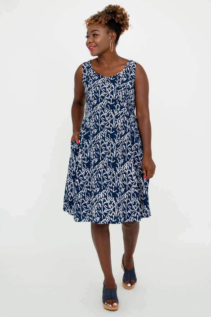 Model standing in a navy and white sleeveless dress with side pockets, looking sideways