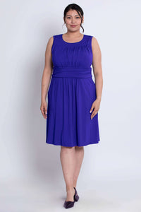 Model wearing a sleeveless royal blue knee-length dress with ruched bodice and pockets