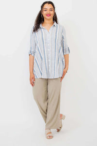 Model standing in blue and white striped tunic with beige pants and sandals