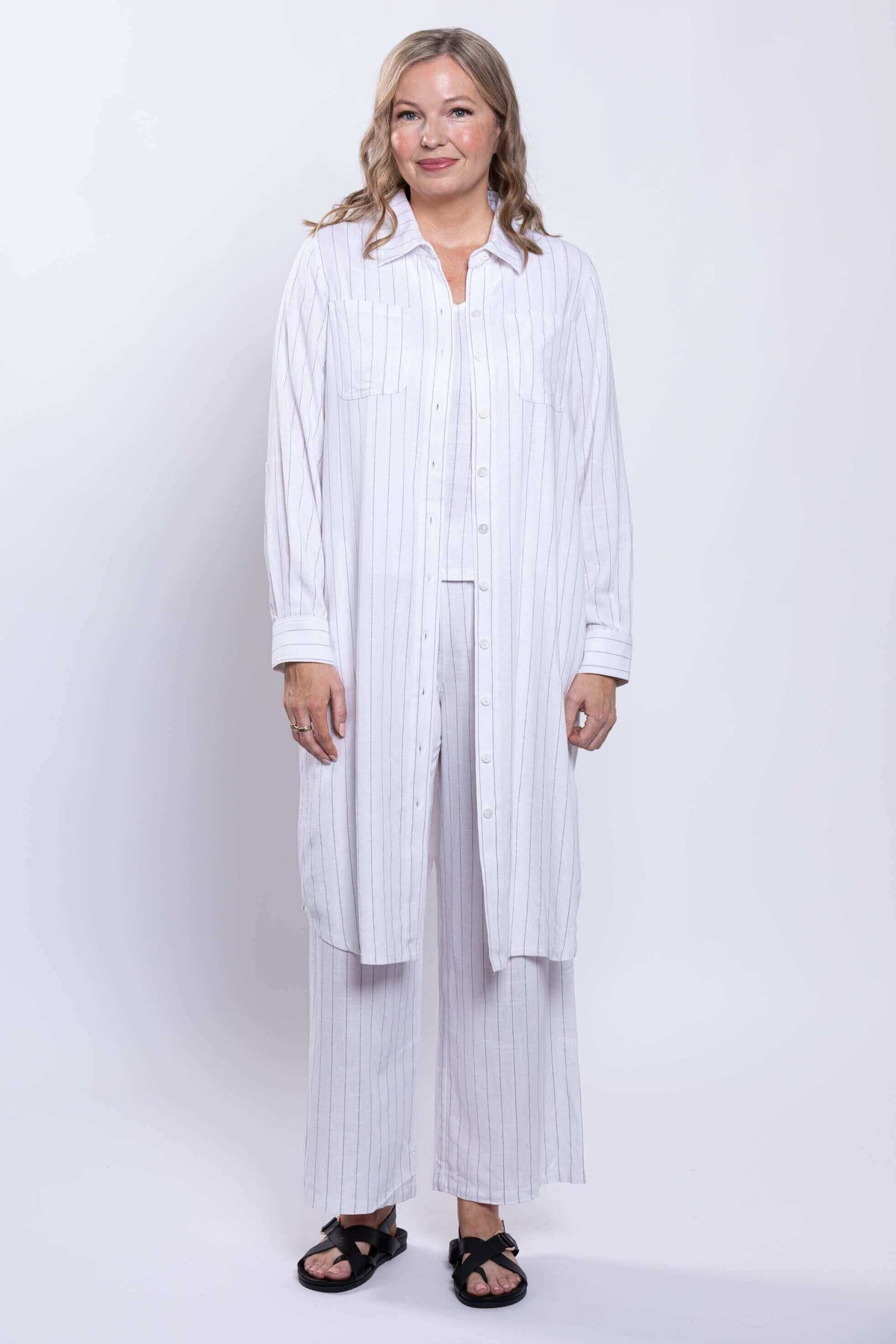 Model in a striped white duster, layering over matching wide-leg pants