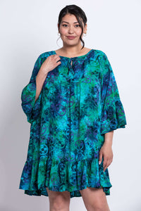 Model posing in Wanda plant-based rayon dress with tie neckline and ruffle details