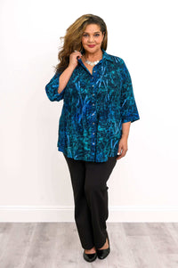 Woman posing in blue smocked button-front shirt and black pants