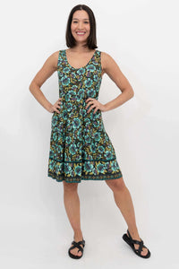 Woman posing hands on hips in a sleeveless green and blue floral tiered dress