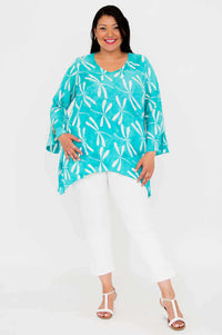 Model posing in aqua dragonfly boho top with white pants and sandals