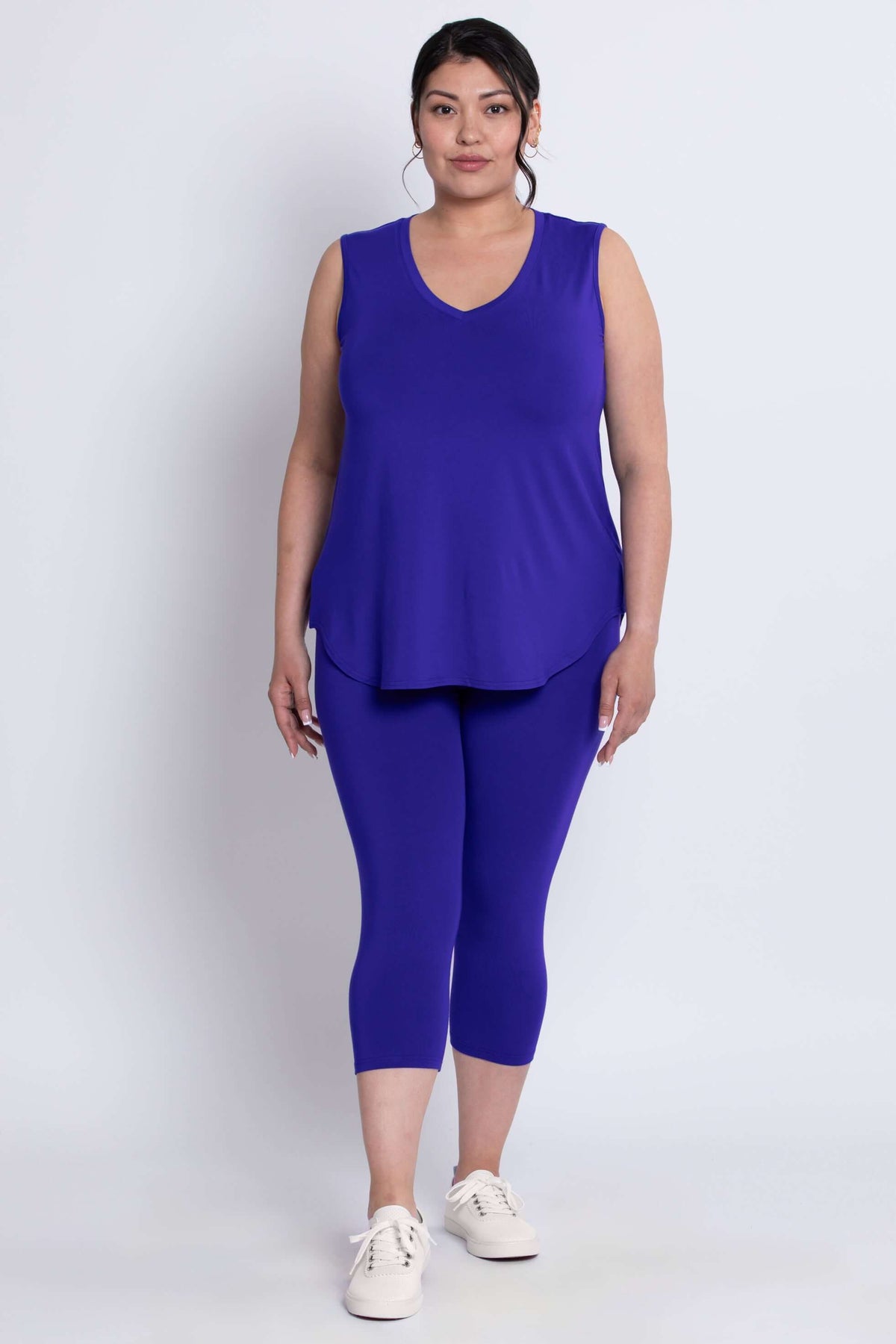 Model in blue capri leggings and sleeveless V-neck top, standing front facing