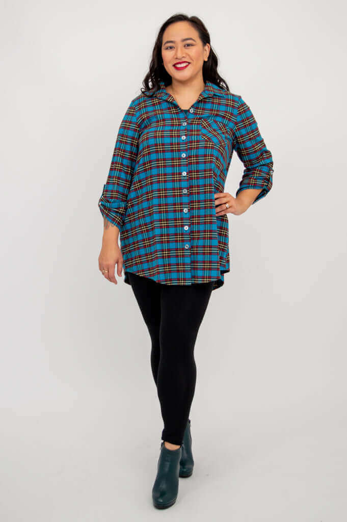 Model posing in blue plaid flannel tunic, one hand on hip