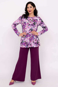 Model posing in purple floral long sleeve tunic and plum trousers