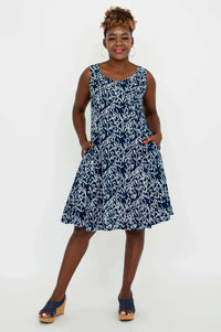 Model posing confidently in a navy and white sleeveless dress, hands in pockets