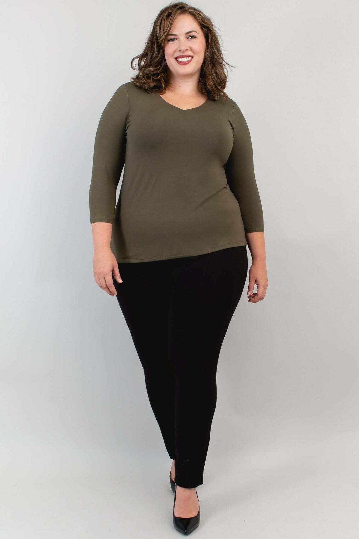 Model posing in olive bamboo top and black pants, slightly side view