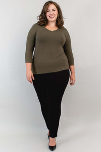 Model posing in olive bamboo top and black pants, slightly side view