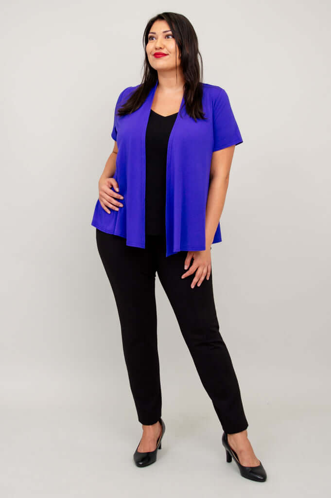Model posing in purple short sleeve open jacket and black pants, hand on hip