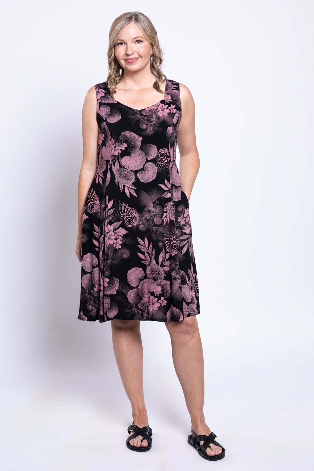 Model posing in sleeveless black dress with pink leaves and flowers