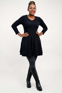 Model posing with hands on hips in a black fit and flare tunic dress