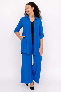 Model posing in a blue blouse-jacket with pockets and matching blue pants