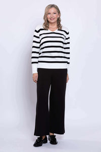 Woman posing in a black and tan Breton stripe V-neck sweater with wide leg pants