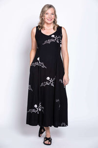 Model in black sleeveless dress with white designs, hands in pockets