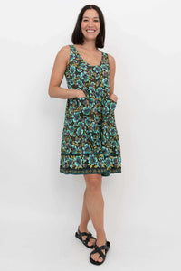 Woman standing with hands in pockets in a green and blue floral dress