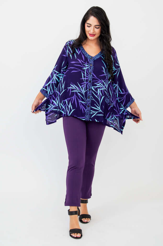 Model displaying flowy sides of purple bamboo print tunic and matching purple pants