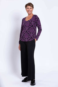 Woman with short hair modeling purple damask print long sleeve top and black pants