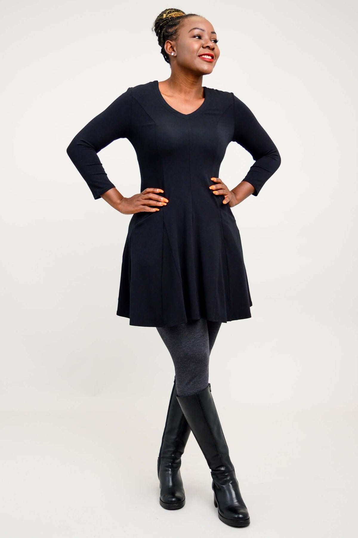 Model looking to the side, smiling and posing in a black tunic dress
