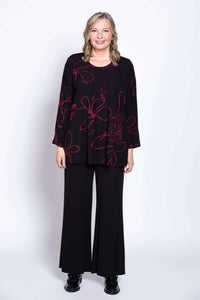 Model smiling in black berry-print blouse and black pants, front view