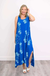 Model smiling in blue floral dress, hand to hair, highlighting dress details