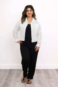 Model standing and posing in a white linen jean jacket and black trousers