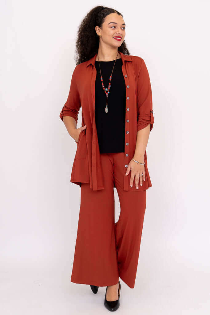 Front view of model in rust bamboo blouse paired with black top and wide leg pants