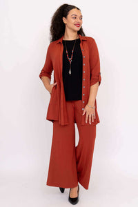 Front view of model in rust bamboo blouse paired with black top and wide leg pants