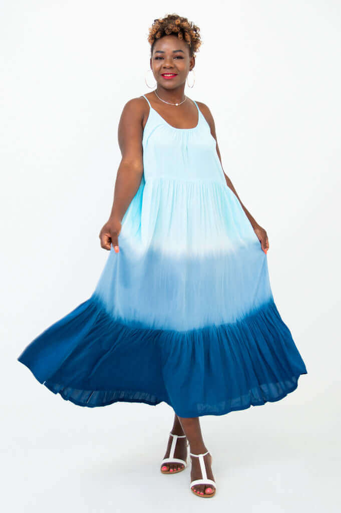 Woman posing and swirling in a blue ombre maxi dress, playful look