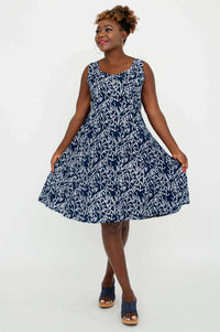 Model showing the flared skirt of a navy and white sleeveless dress, angled front view