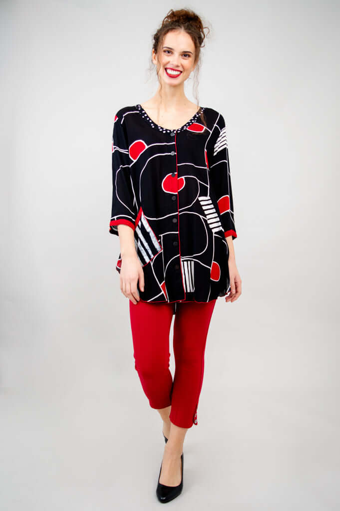 Model walking forward in Aku Top, button-up with black, red, and white abstract print