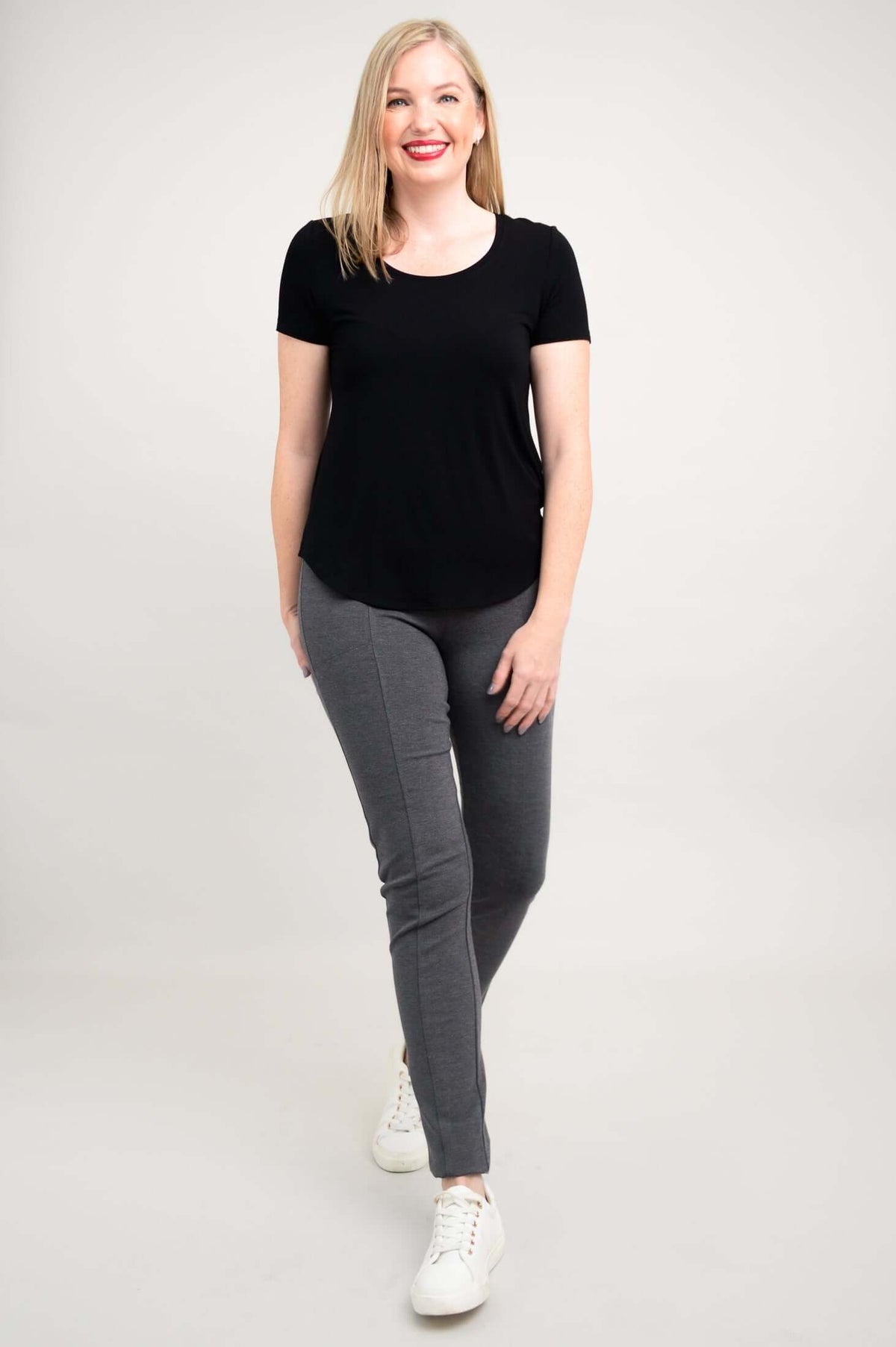 Woman walking forward in black scoop neck tee and grey pants