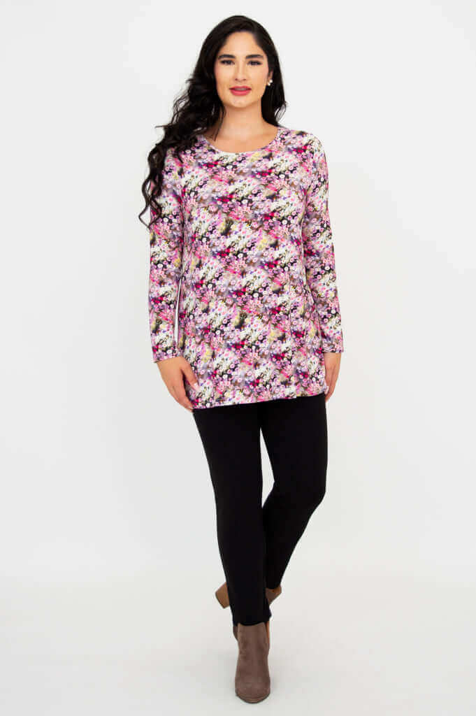Model walking in a long sleeve floral tunic paired with black pants