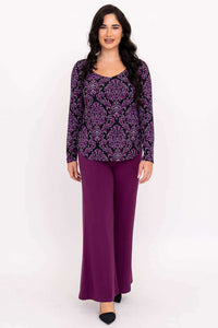 Woman walking forward in purple damask top and matching purple pants