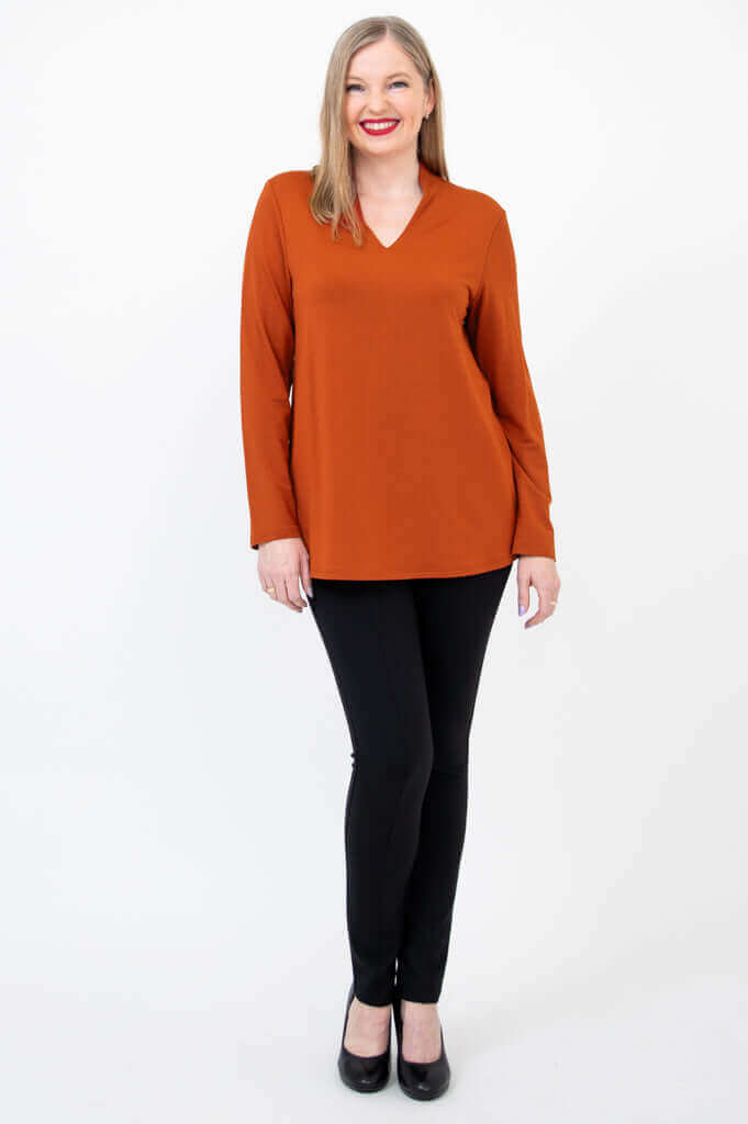 Model standing in rust bamboo V-neck long sleeve top and black pants