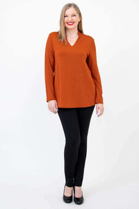Model standing in rust bamboo V-neck long sleeve top and black pants