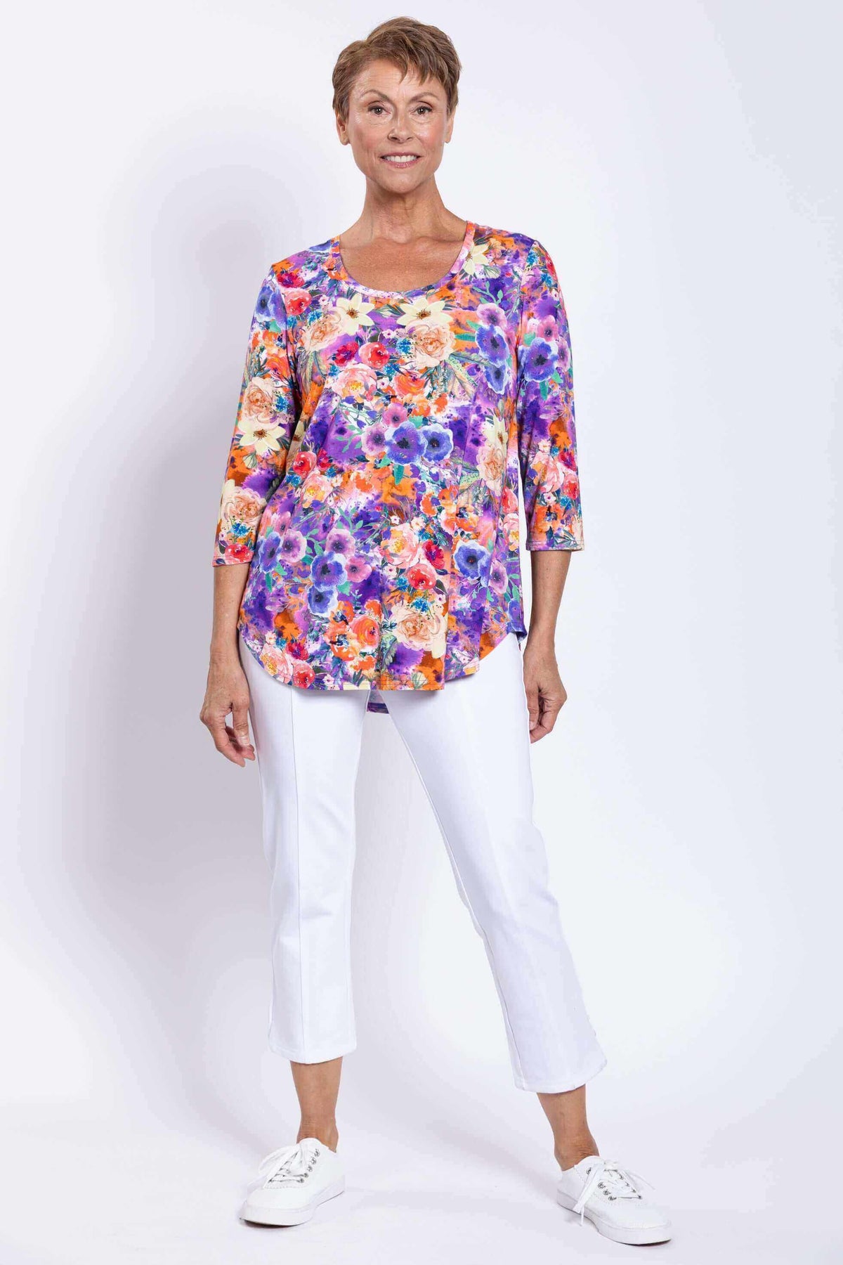 Model smiling in a floral Jazz bamboo top and white cropped pants