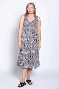 Front view of a woman in a sleeveless black and white print dress paired with black sandals
