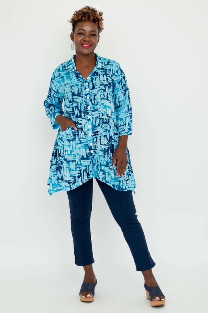Woman modeling Laney Blouse in turquoise brushstroke pattern with one hand in pocket