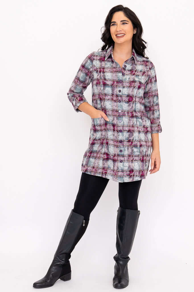 Woman posing in a plaid flannel tunic shirt with leggings and tall black boots