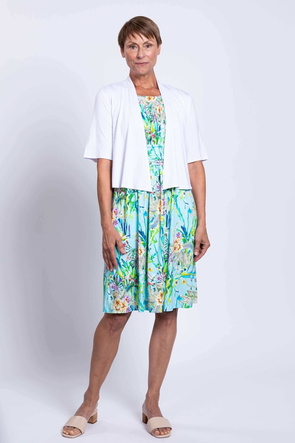 Model wearing blue floral dress with white cardigan, front view