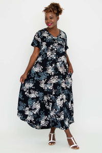 Model wearing a black floral A-line midi dress with short sleeves and swingy skirt