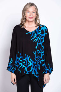 Model wearing a black flowy top with bold blue coral print, close-up view
