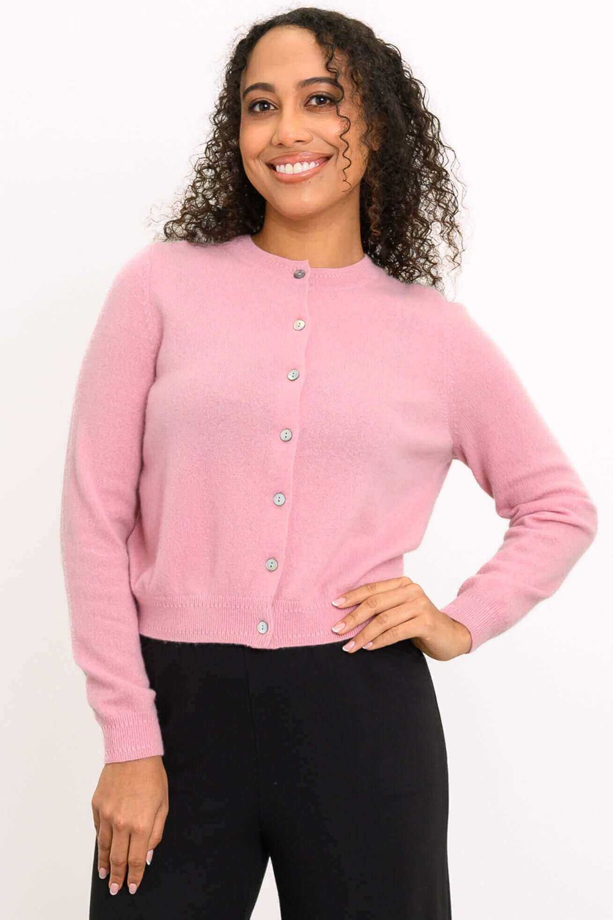 Model wearing a pink cashmere cardigan with crew neckline and button front