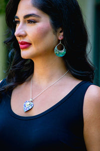 Woman wearing abalone and silver crescent earrings with matching heart necklace