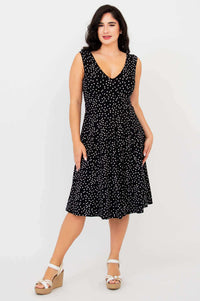 Front view of woman modeling a black and white polka dot fit and flare dress