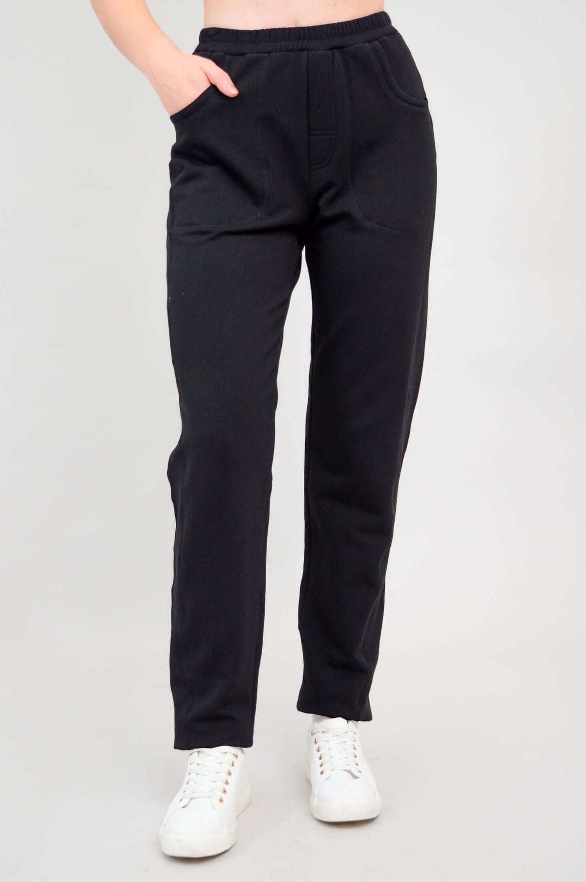 Front view of model wearing black bamboo fleece track pants with hand in pocket